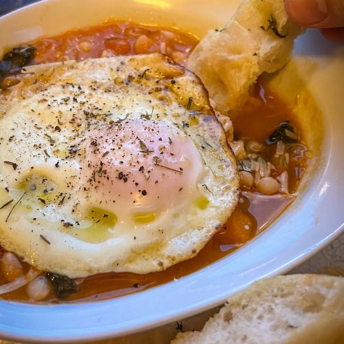 A bowl of tomato & white bean soup topped with an egg